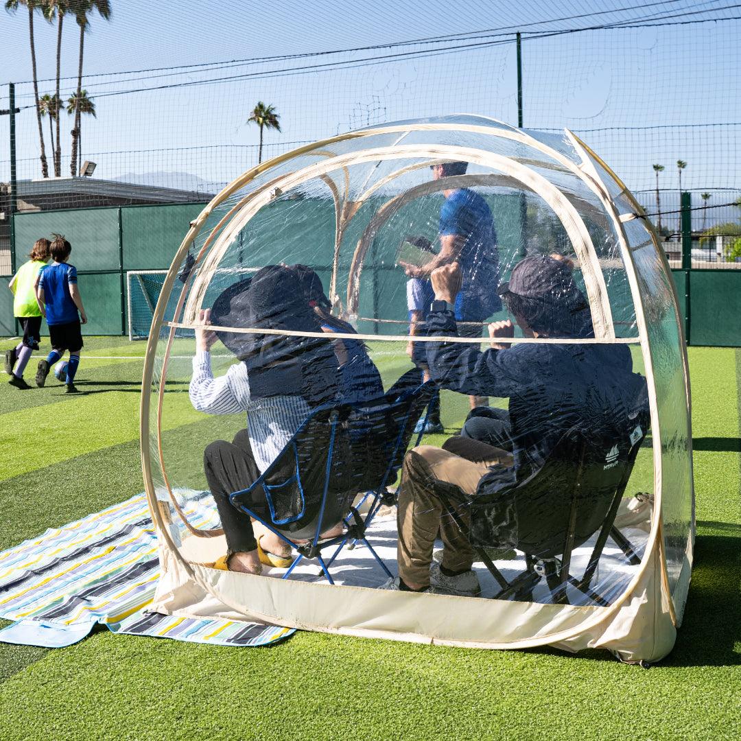 4 people sitting inside a weatherproof pod, cheering for the competition